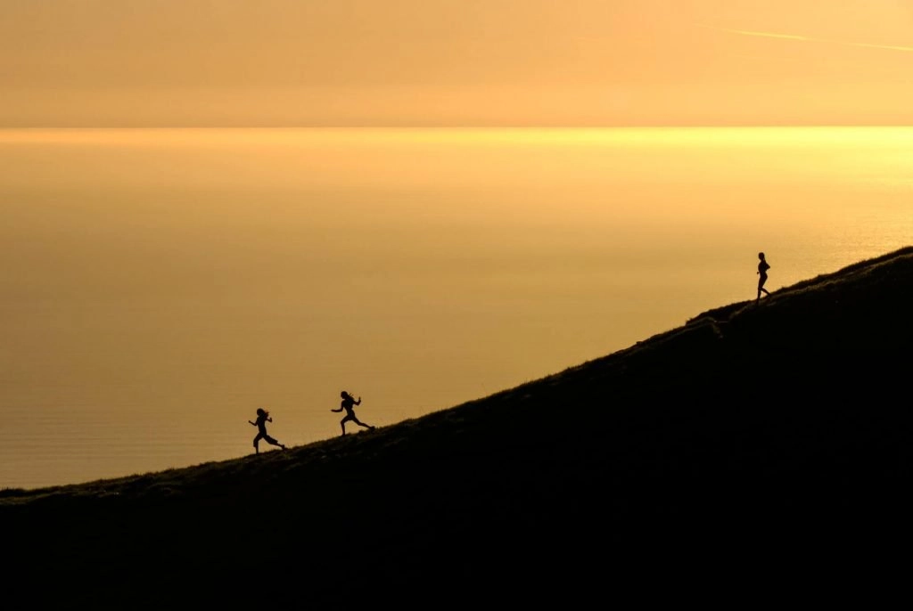 hikers running down hill during sunset