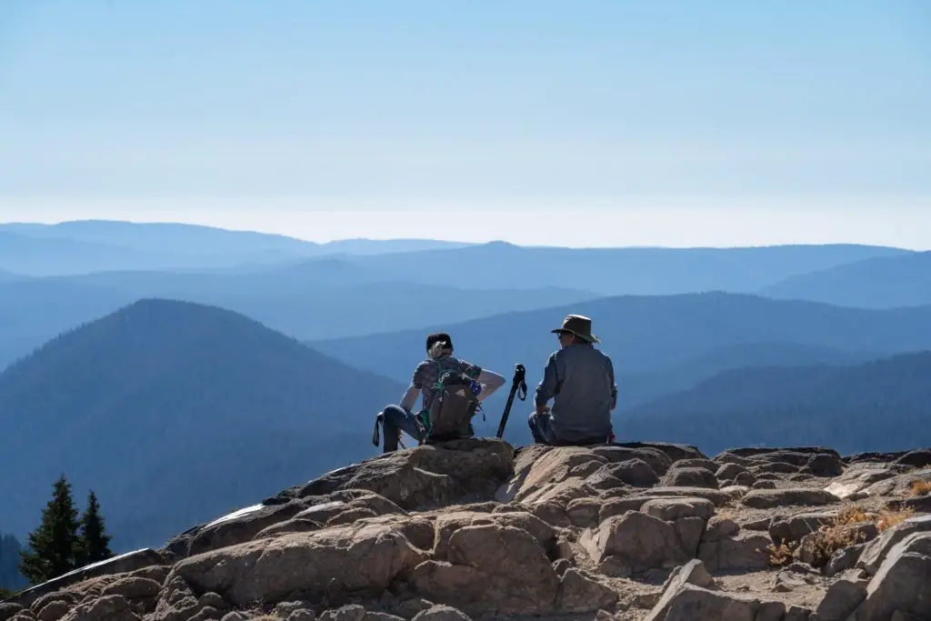 hikers sitting on rocky summit enjoying views