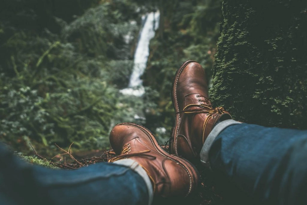 hiker sitting down when legs streched near waterfall