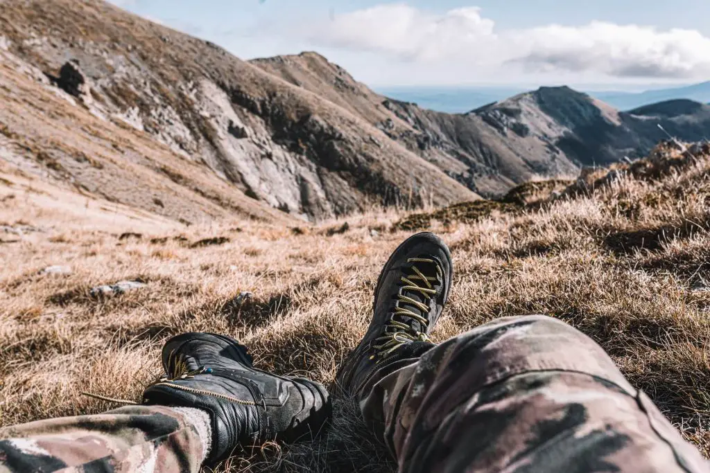 hiker stretching legs while sitting down staring at mountains
