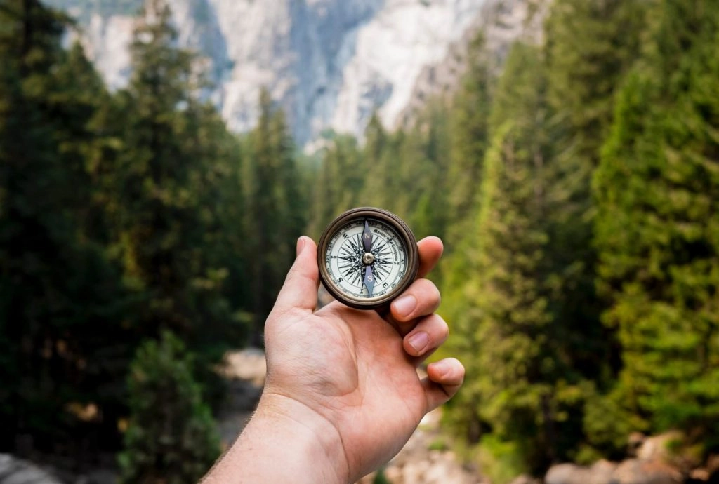 hand holding up compass in the mountains