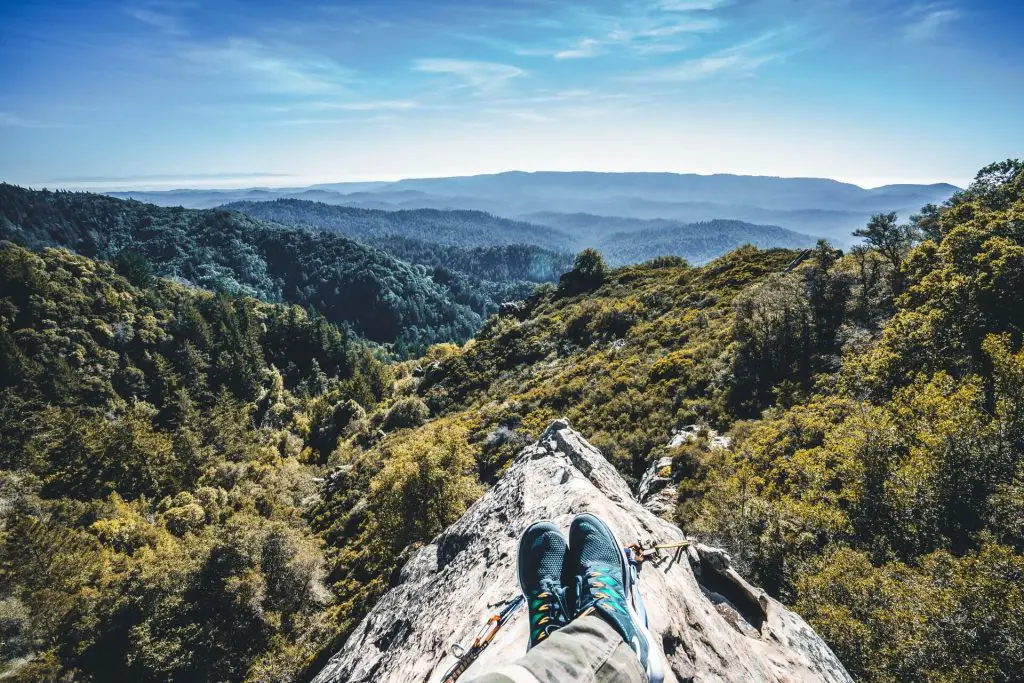hiker with legs streched out enjoying view of forest valley