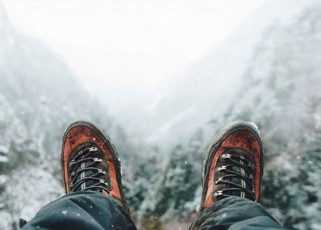 hiker sitting with boots in the air on snow field