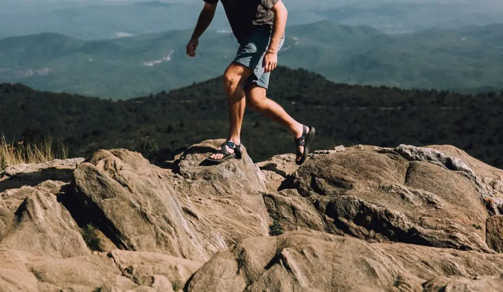 hiker in jean shorts going up rocks