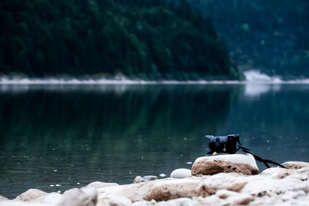 mirrorless camera on rock by lake