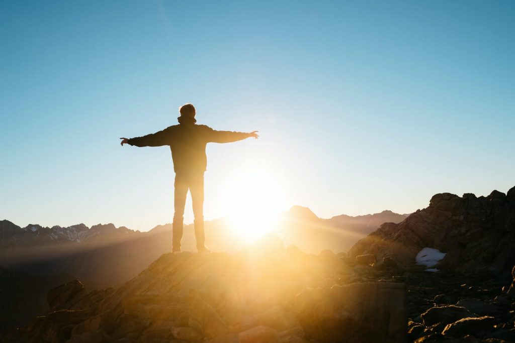 hiker standing on peak at sunrise