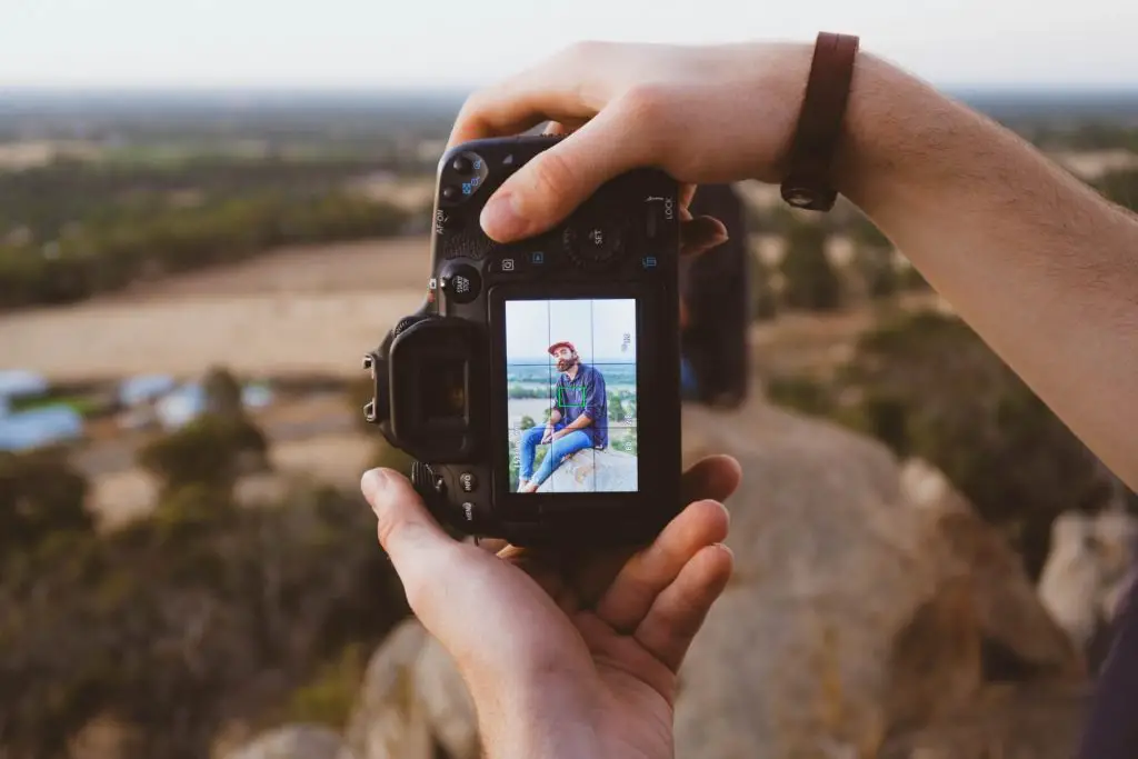 person using camera to photograph backpacker