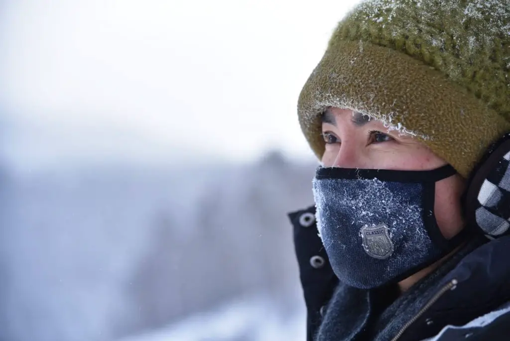female hiker with a face covering in the snow