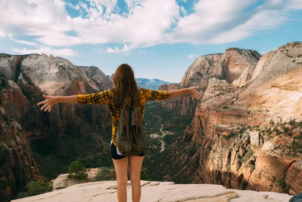 women hiker with open arms facing zion canyon overlook