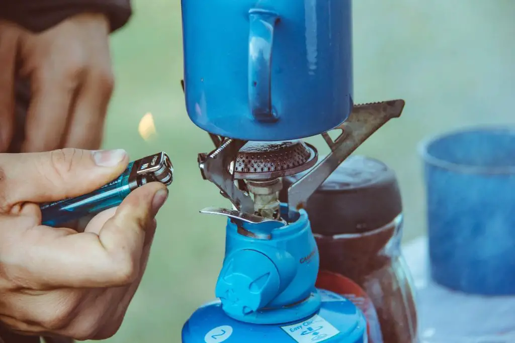 person lighting up camping stove