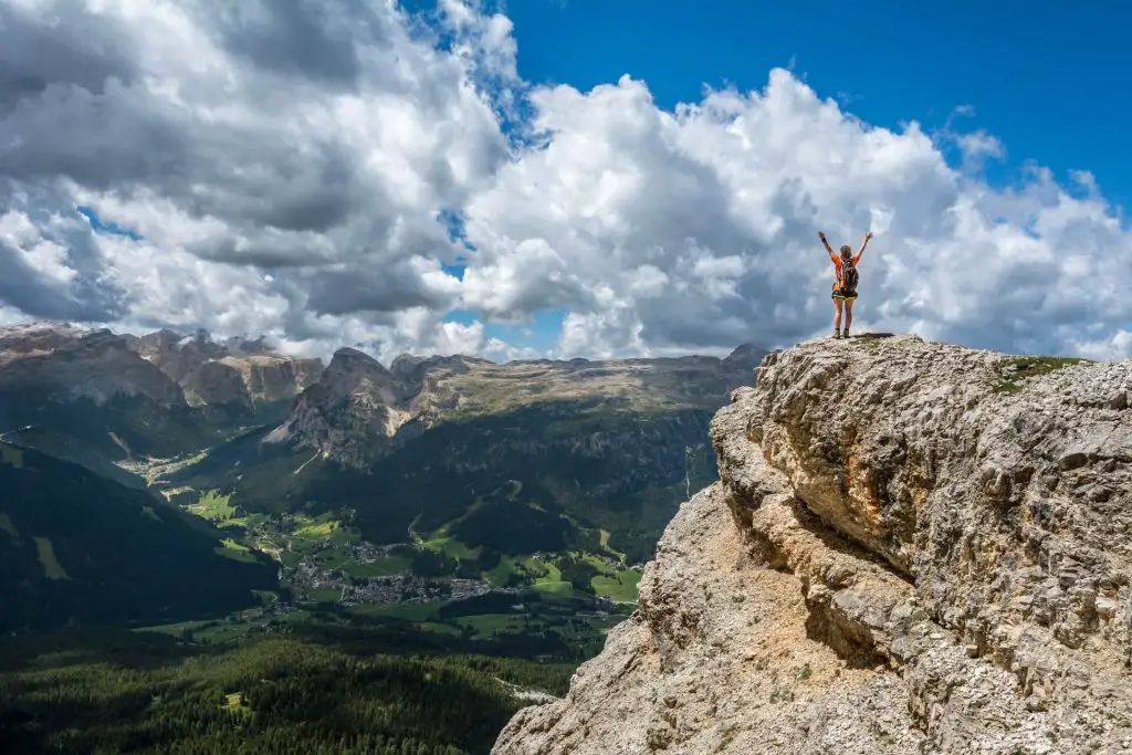 female hiker with arms up on mountain peak