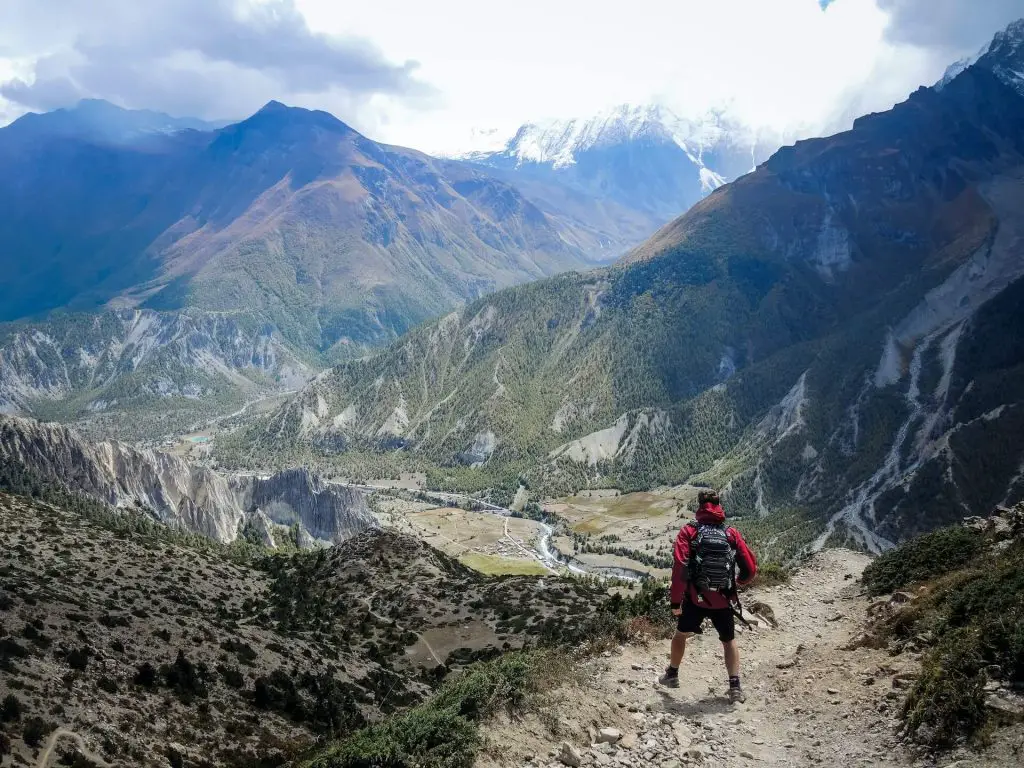 hiker standing on trail looking at mountains