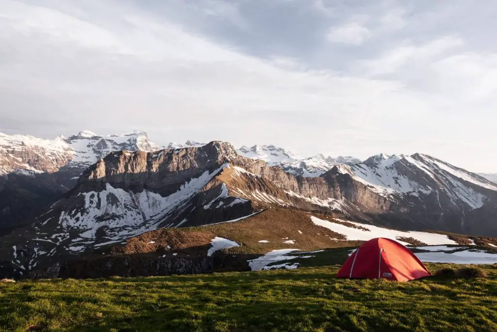 red tent setup by snowy mountains